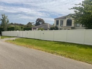 Full Privacy PVC fence with Sliding gate, single gate, & letterbox on sloped block.