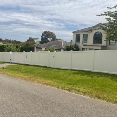 Full Privacy PVC fence with Sliding gate, single gate, & letterbox on sloped block.